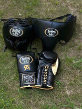 No Boxing No Life professional custom 3-piece boxing sparring gear set featuring matching lace-up gloves with gold CA logo, a cheek headguard, and a groinguard in premium black leather with metallic gold trim accents on grass.