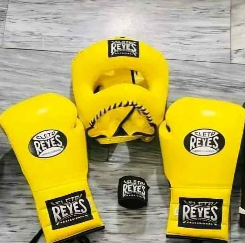 Official Cleto Reyes professional 3-piece boxing sparring gear set featuring matching lace-up gloves, a cheek protector headguard, and a groinguard in uniform vibrant yellow leather.