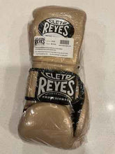 Official Cleto Reyes professional lace-up training boxing gloves in gold metallic leather featuring a high-sheen champagne finish with black printed brand logos, brand new in protective plastic packaging.