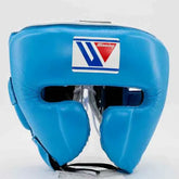Official Winning FG-2900 professional boxing cheek-protection headgear in sky blue premium leather featuring the iconic brand logo crest patch centered on the forehead.