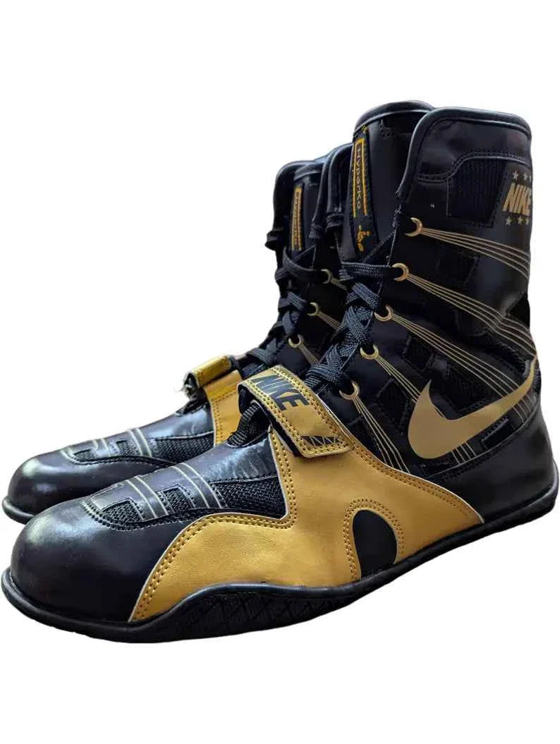 Professional Nike Hyperko 1 boxing boots in sleek black and metallic gold featuring Flywire support and a forefoot strap.