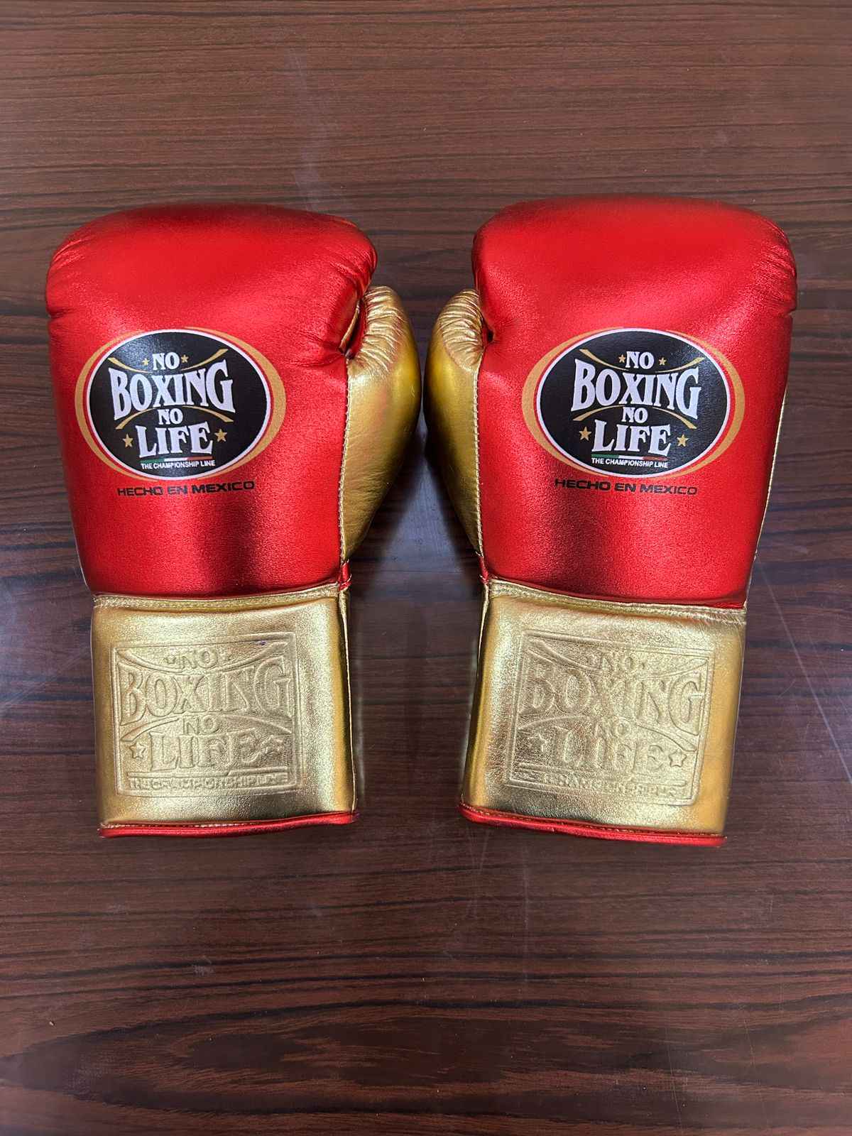 No Boxing No Life red and gold leather boxing gloves with brand logo on wooden surface