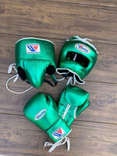 Custom Winning professional 3-piece boxing sparring gear set in a matching shimmering metallic green premium leather colorway, featuring lace-up training gloves, a face guard headgear, and a groin protector arranged on a wooden floor.