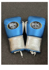 Official No Boxing No Life professional lace-up training boxing gloves in metallic blue leather featuring metallic silver cuffs, white inner palms, and the iconic oval brand logo patches on the knuckles.