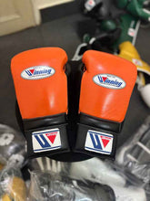 Custom Winning professional lace-up training boxing gloves in a vibrant orange and black leather colorway featuring the iconic brand logo patches on the knuckles and cuffs.
