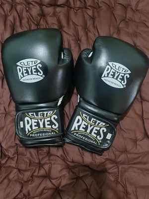 Official Cleto Reyes professional hook-and-loop training boxing gloves in satin black metallic leather featuring a high-sheen dark charcoal finish with white printed brand logos and stitched wrist patches.