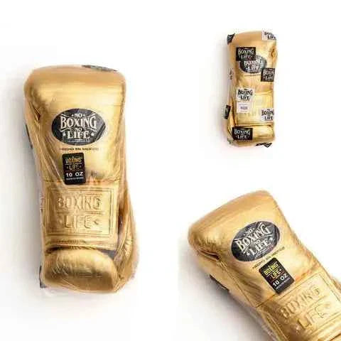 Official No Boxing No Life professional lace-up boxing gloves in metallic gold leather showing the iconic black oval brand logo patch on the knuckles and an embossed logo on the cuff.