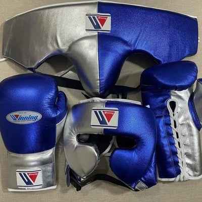 Custom Winning professional 3-piece boxing sparring gear set featuring matching lace-up gloves, a cheek headguard, and a groinguard in an asymmetrical metallic royal blue and metallic silver split leather colorway.