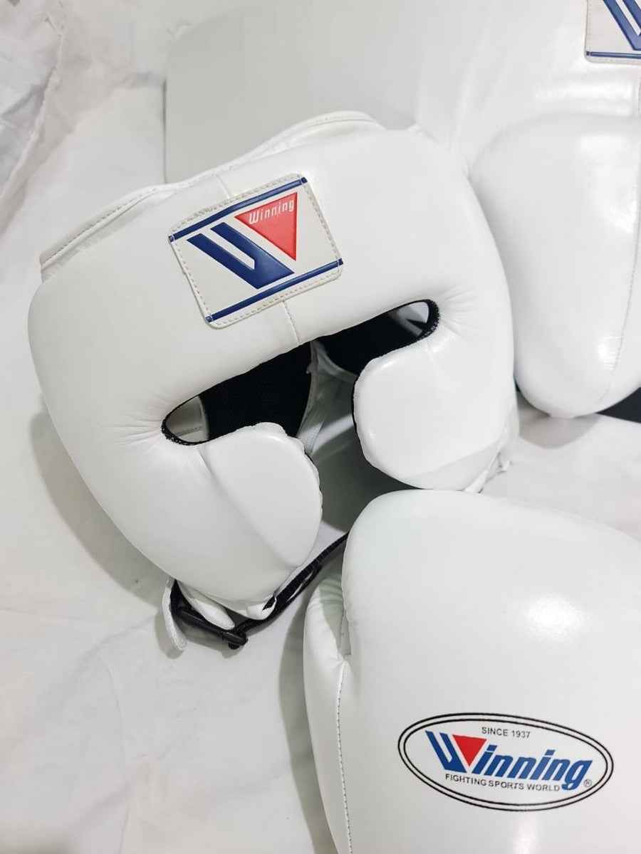 Official Winning professional 3-piece boxing sparring gear set in a matching classic white premium leather colorway, featuring lace-up training gloves, a face guard headgear, and a groin protector grouped together over a white sheet backdrop.
