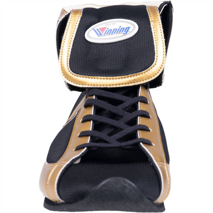 Close-up of Winning short-cut boxing boot showing black and gold fabric construction, laces, and oval Winning brand patch