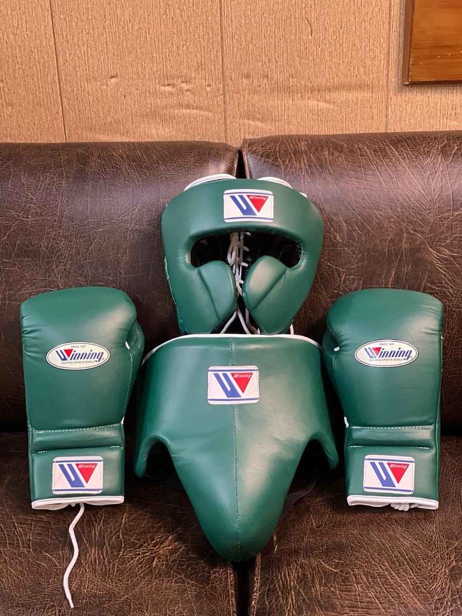 Winning professional custom 3-piece boxing sparring gear set featuring a matching lace-up glove pair, full-face headguard, and groinguard in uniform British racing green leather with white trim accents.