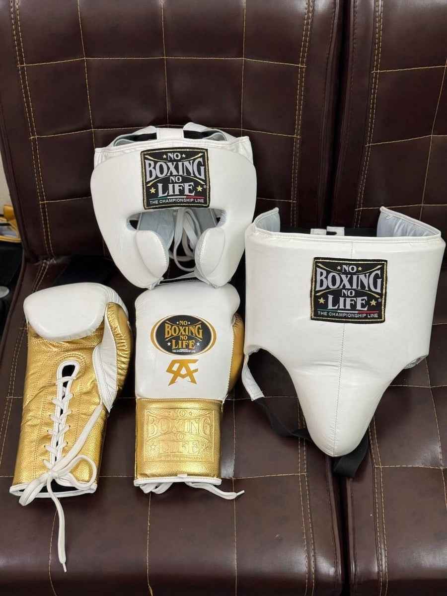 Official No Boxing No Life professional 3-piece boxing sparring gear set featuring white and metallic gold lace-up gloves, a white cheek protection headgear, and a white groin protector grouped together.