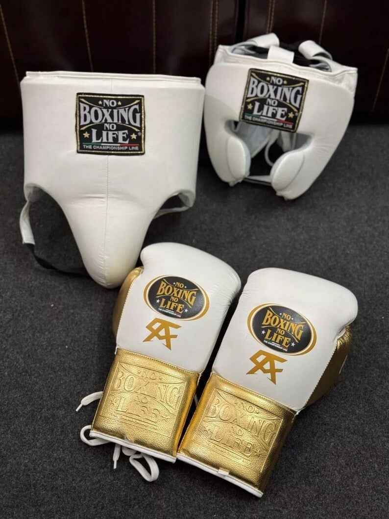 Official No Boxing No Life professional 3-piece boxing sparring gear set featuring white and metallic gold lace-up gloves, a white cheek protection headgear, and a white groin protector grouped together.