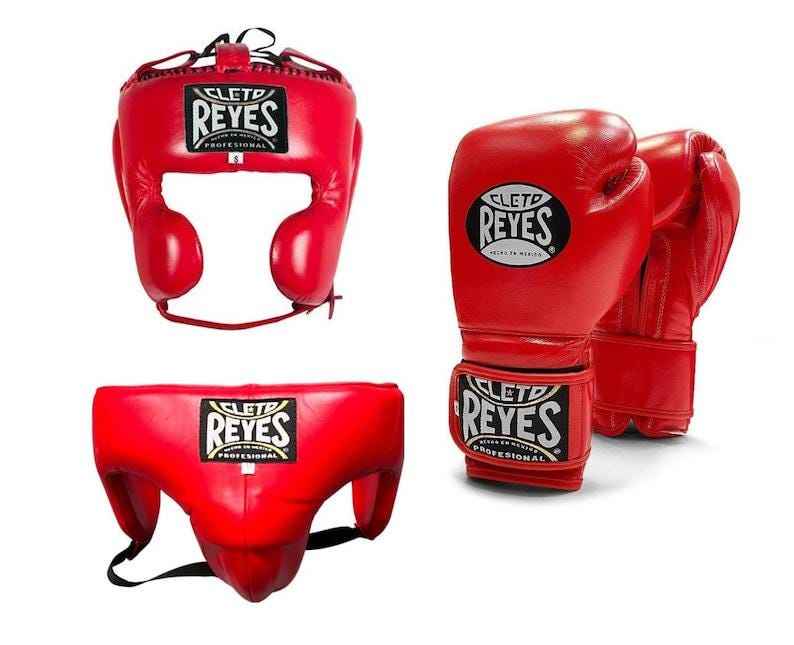 Official Cleto Reyes professional 3-piece boxing sparring gear set featuring matching hook-and-loop gloves, a cheek protector headguard, and a groinguard in uniform classic red leather.