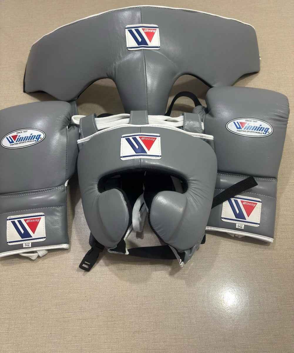 Winning professional custom 3-piece boxing sparring gear set featuring a matching lace-up glove pair, full-face headguard, and groinguard in uniform slate gray leather with white trim accents.