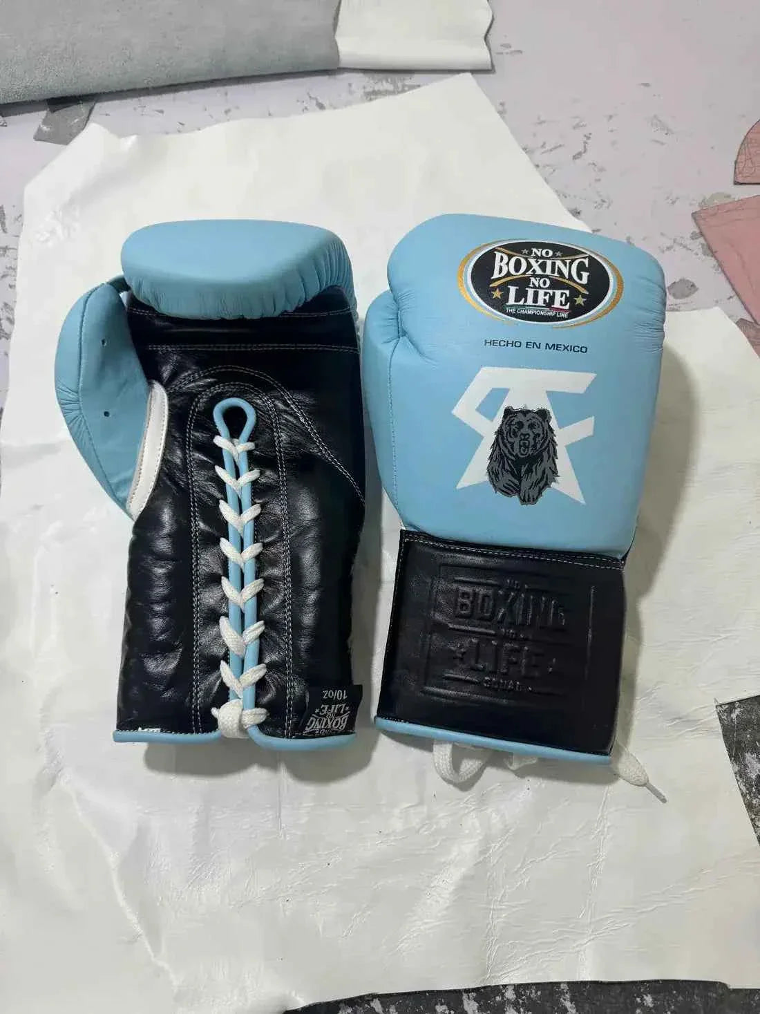 Custom No Boxing No Life professional lace-up boxing gloves in sky blue leather featuring white signature graphics, a detailed black grizzly bear emblem, and contrasting black leather cuffs.