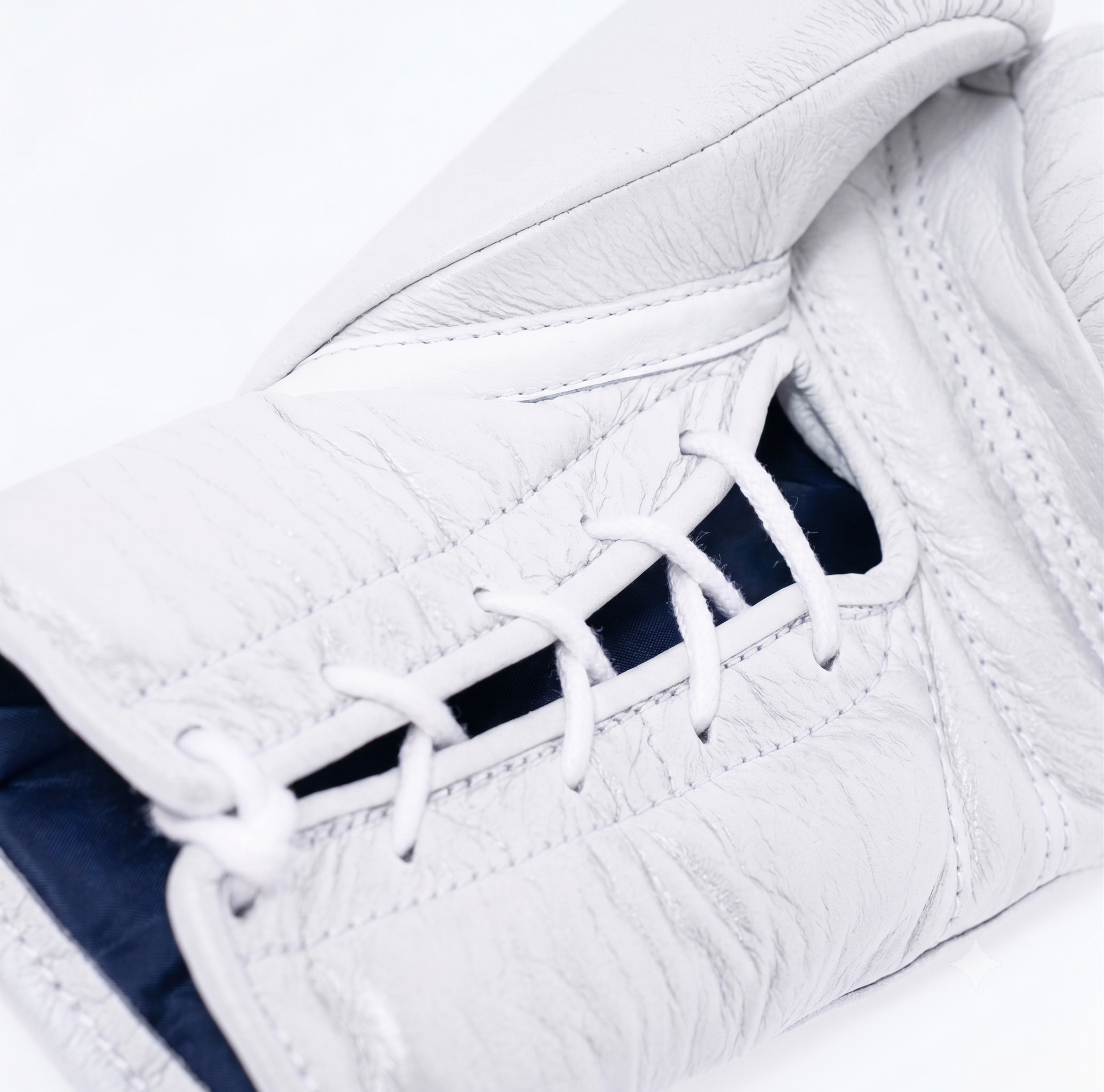 Close-up of a white leather hockey glove showing the lace-up closure with white laces and a dark navy interior lining.