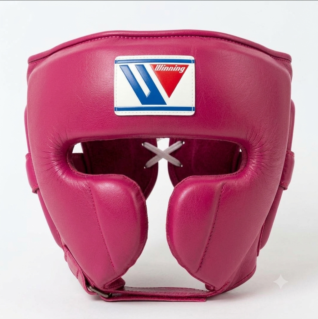 A pink leather boxing headguard with a white, blue, and red Winning logo patch on the forehead, set against a plain light gray background.