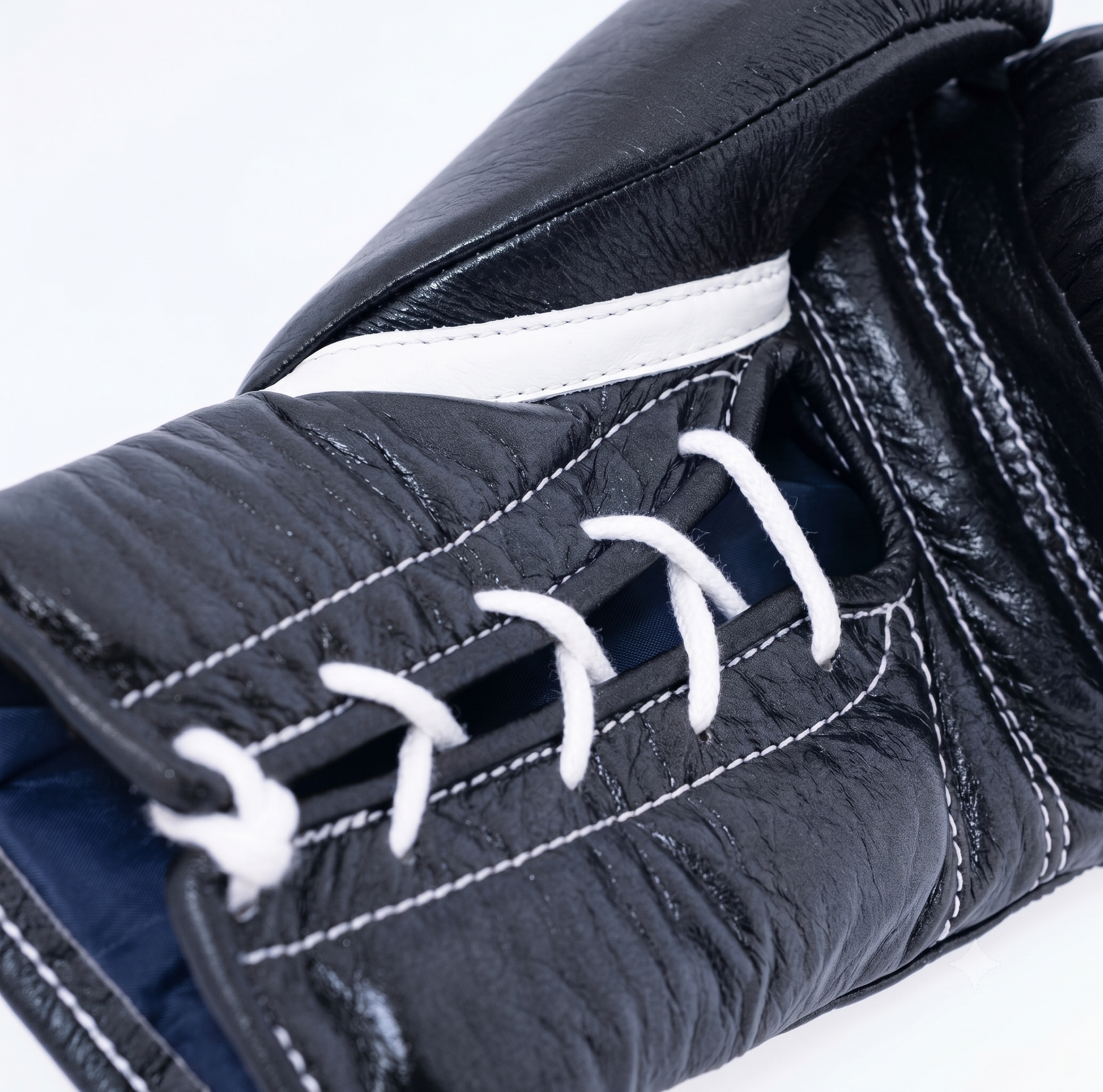 Close-up of a black leather hockey glove with white laces and white contrast stitching, showing the textured leather and interior lining against a white background.