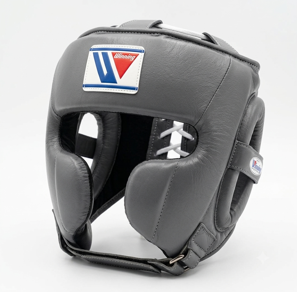 A dark gray leather boxing headguard with a white, blue, and red 'Willett' logo patch on the forehead, shown on a light gray background.