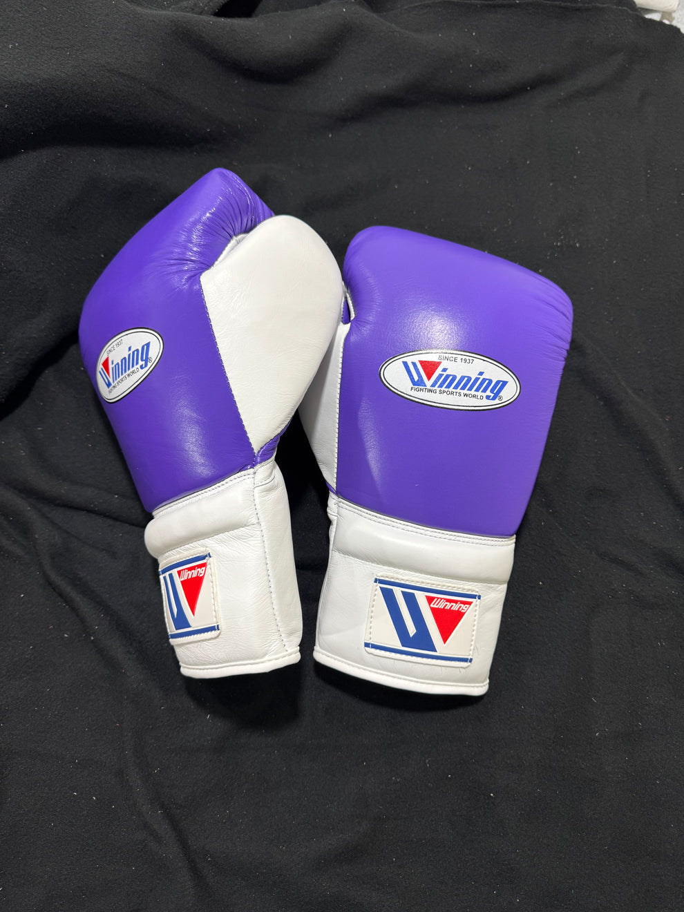 Custom Winning professional lace-up training boxing gloves in a vibrant purple and white leather colorway featuring white laces and the iconic brand logo crest on the cuffs.