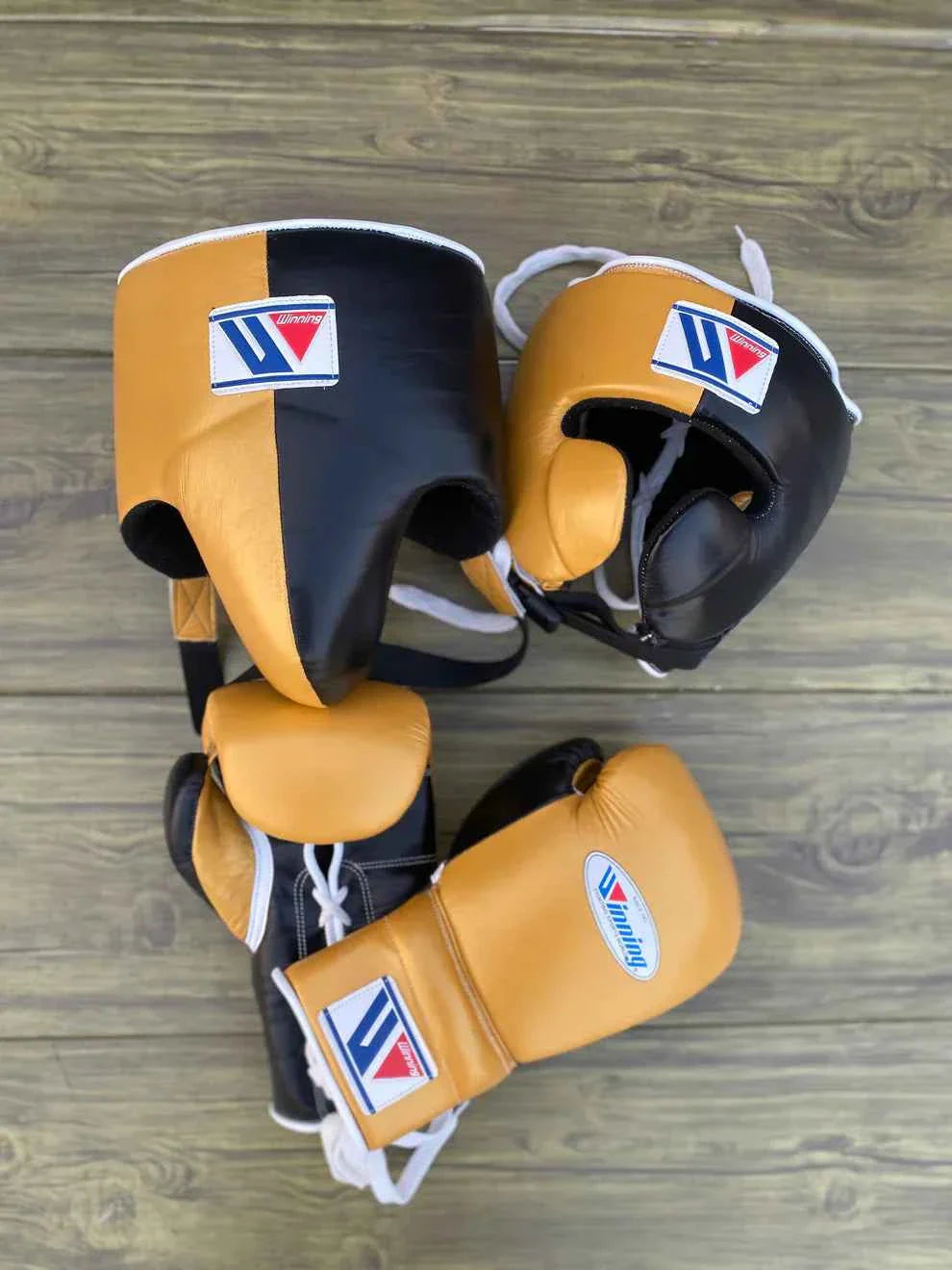 Authentic Winning professional boxing set in custom gold and black leather with lace-up gloves and face-bar headgear.
