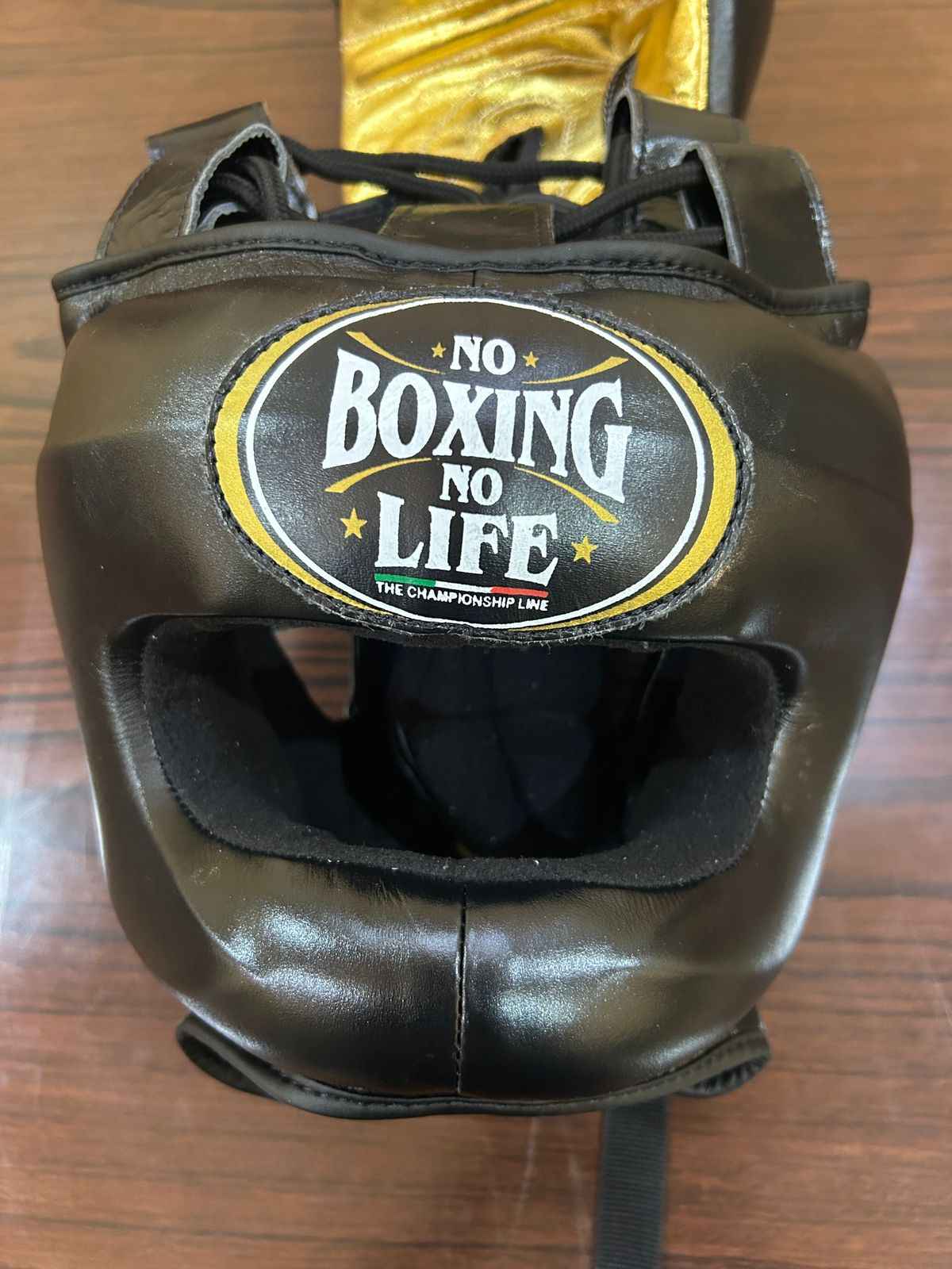 Black boxing headgear with 'No Boxing No Life' logo on a wooden surface
