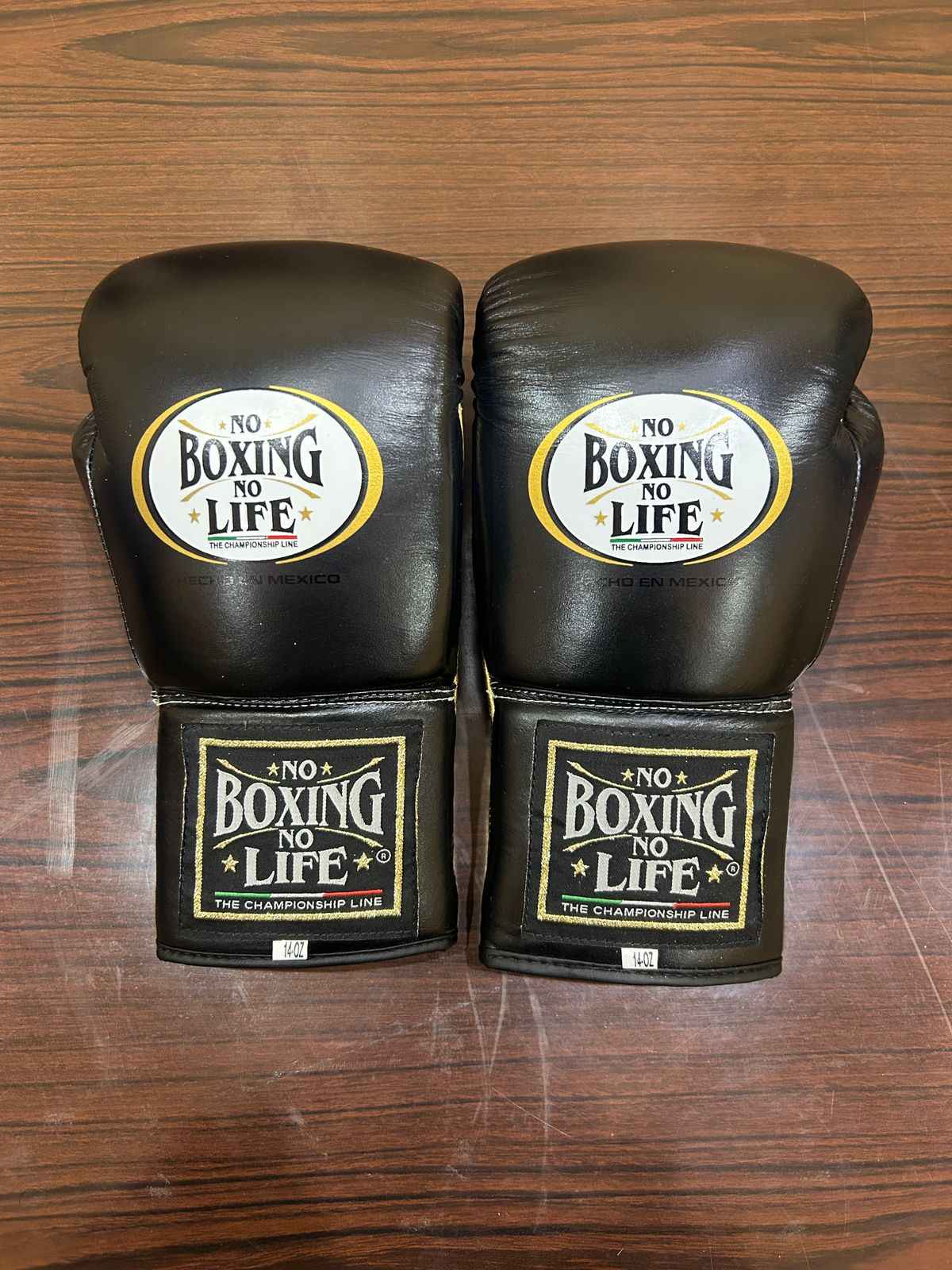 No Boxing No Life matte black leather boxing gloves with brand logo on wooden surface