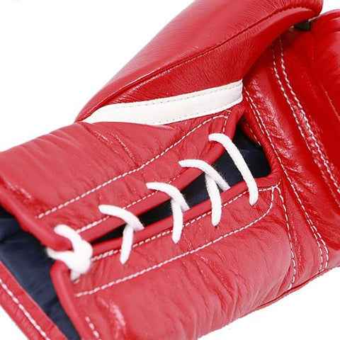 Close-up of a red boxing glove with white laces on a white background