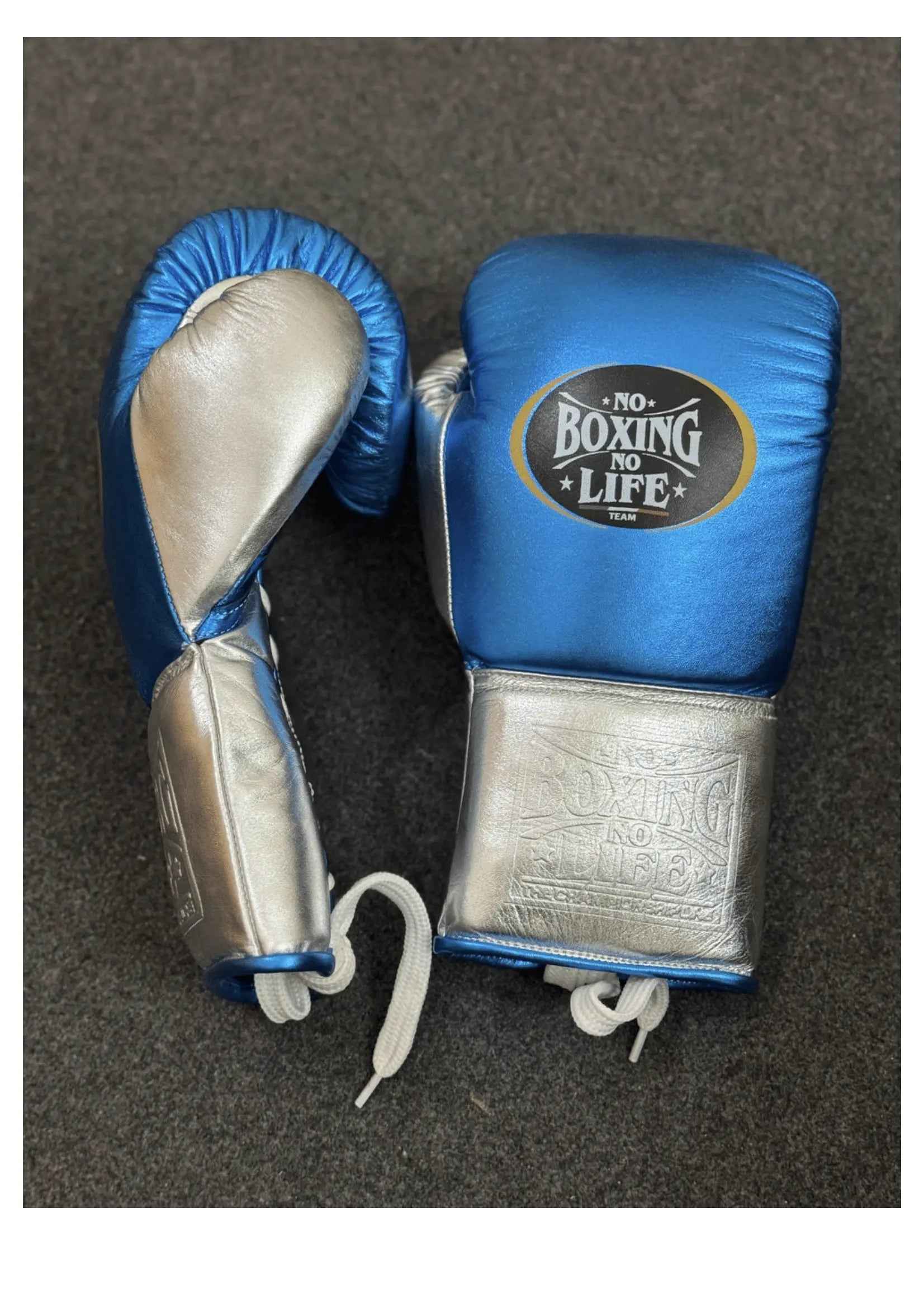 Official No Boxing No Life professional lace-up training boxing gloves in metallic blue leather featuring metallic silver cuffs, white inner palms, and the iconic oval brand logo patches on the knuckles.