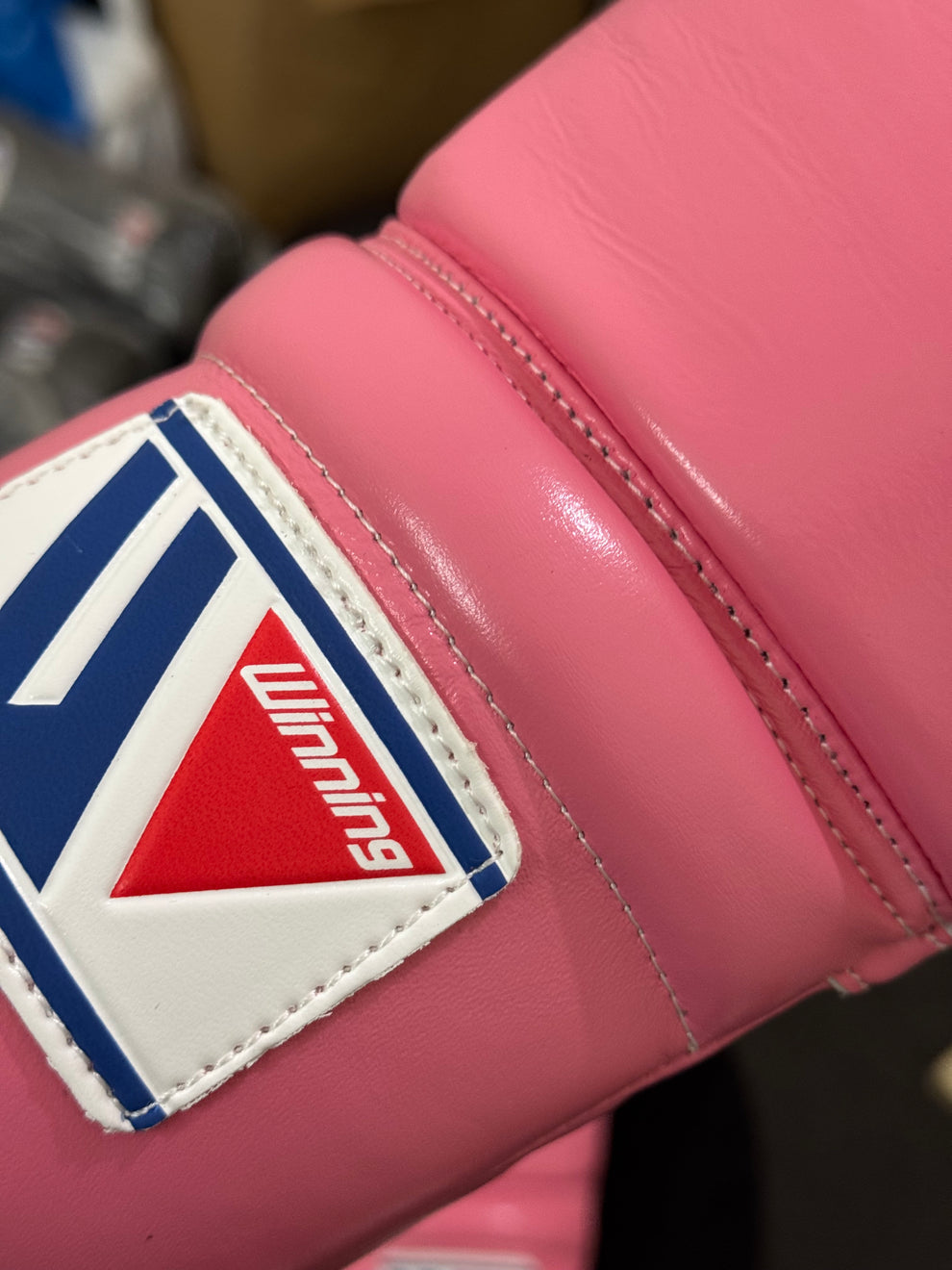 Pink boxing glove with a visible brand logo on a blurred background