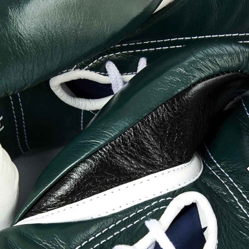 Close-up of green leather shoes with white laces and stitching details.