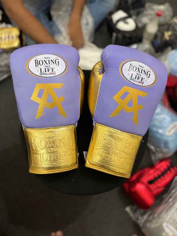 Official No Boxing No Life professional lace-up boxing gloves in premium lavender and metallic gold leather featuring a gold Canelo Alvarez CA logo printed below the brand insignia.