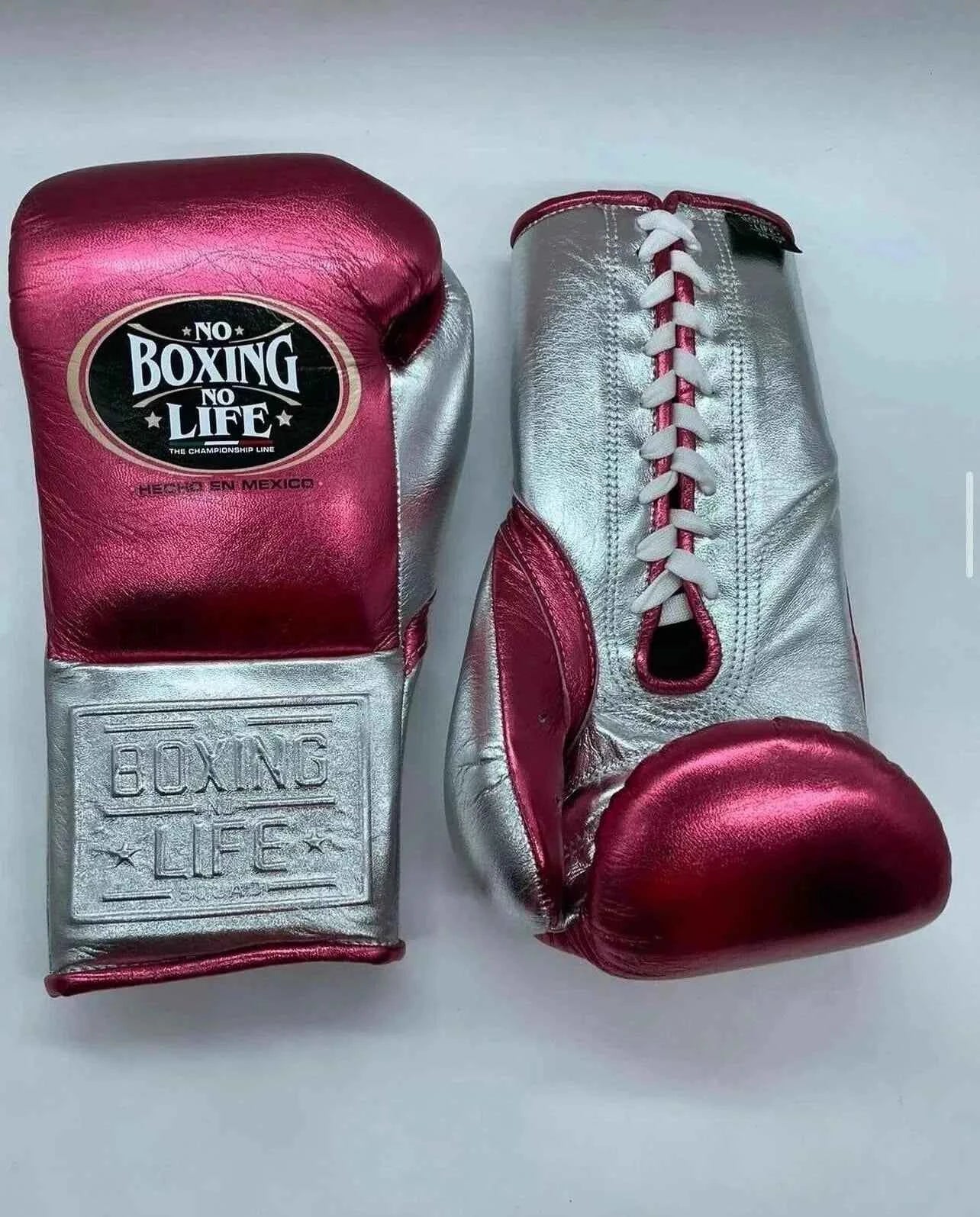 No Boxing No Life professional lace-up boxing gloves in metallic pink leather with a metallic silver thumb, palm, and cuff area featuring the official brand patch and contrasting white laces.